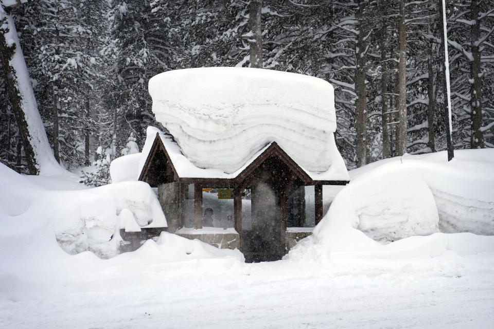 A person sits in a snow-covered bus stop on Feb. 24, 2023, in Olympic Valley, Calif.  / Credit: John Locher / AP