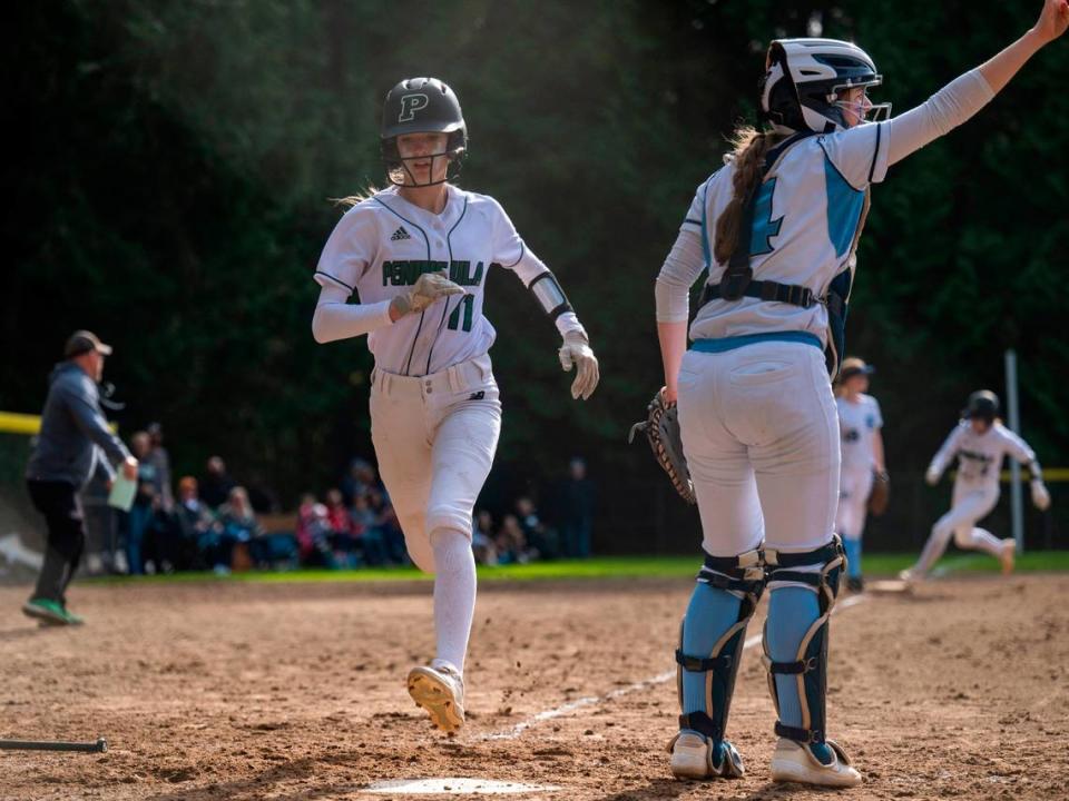 Peninsula’s Glory Estabrook scores and Payton Davis rounds third base on her way home to score off of a 2-run single by Ava Miranda during the bottom of the fifth inning as Gig Harbor catcher Sarah Holland looks on during a 3A South Sound Conference game on Wednesday, April 6, 2022, at Peninsula High School in Gig Harbor, Wash.