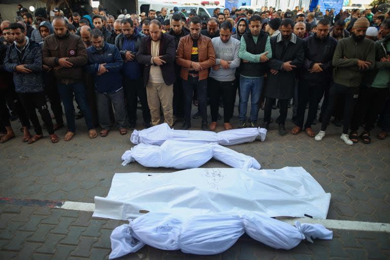 Palestinos oran junto a cuerpos amortajados de personas muertas tras un bombardeo israelí, en un hospital de Deir al-Balah, en el centro de la Franja de Gaza, el 20 de diciembre de 2023