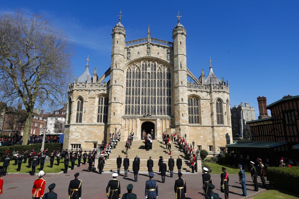 A minute of silence is observed outside St. George's Chapel at Windsor Castle as military and royal family members stand.