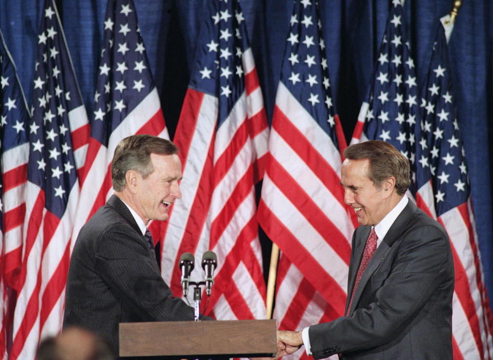 FILE - President George H.W. Bush, left, and Senate Minority Leader Bob Dole of Kansas shake hands at a dinner hosted by Dole in the president's honor in Washington, Nov. 10, 1992.Bob Dole, who overcame disabling war wounds to become a sharp-tongued Senate leader from Kansas, a Republican presidential candidate and then a symbol and celebrant of his dwindling generation of World War II veterans, has died. He was 98. His wife, Elizabeth Dole, posted the announcement Sunday, Dec. 5, 2021, on Twitter. (AP Photo/J. Scott Applewhite, File)