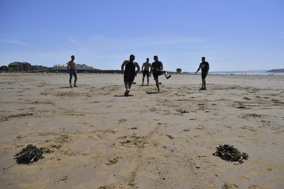 Men play football as they enjoy the hot weather on the beach, in Weston-super-Mare, England, Wednesday May 20, 2020. Lockdown restrictions due to the coronavirus outbreak have been relaxed allowing unlimited outdoor exercise and activities such as sunbathing. The Met Office has predicted the hottest day of the year so far with temperatures set to hit 28C (82.4F). (Ben Birchall/PA via AP)