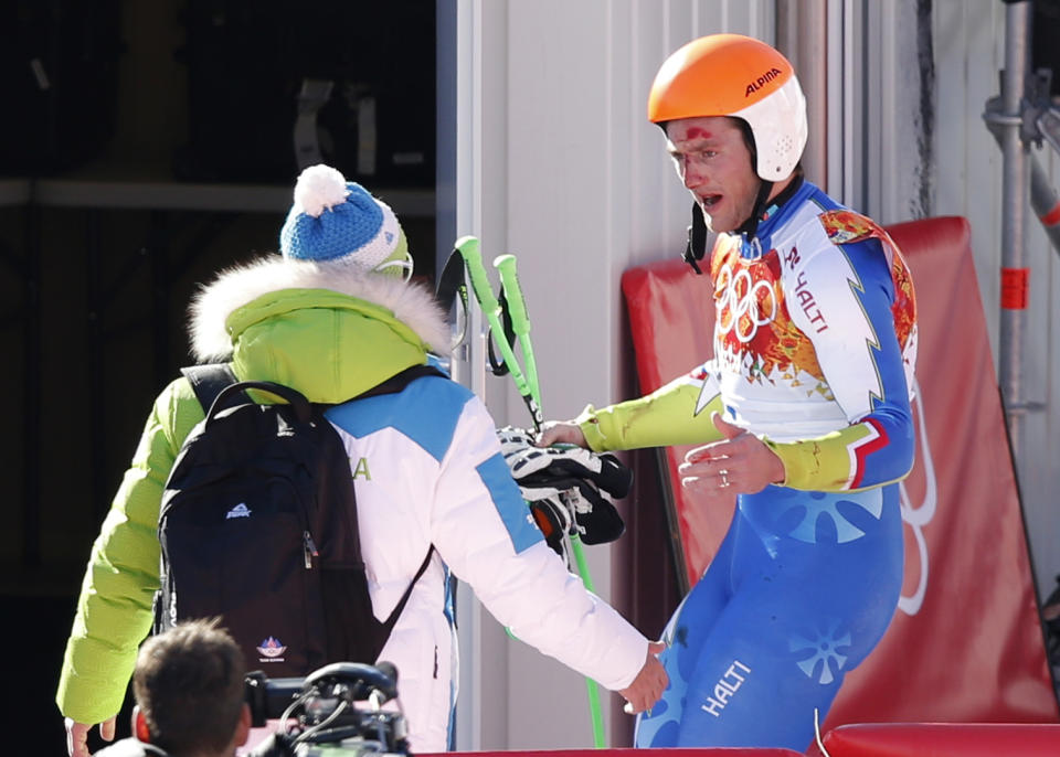 Slovenia's Rok Perko talks to a coach in the finish area after crashing in a men's downhill training run for the Sochi 2014 Winter Olympics, Saturday, Feb. 8, 2014, in Krasnaya Polyana, Russia. (AP Photo/Christophe Ena)
