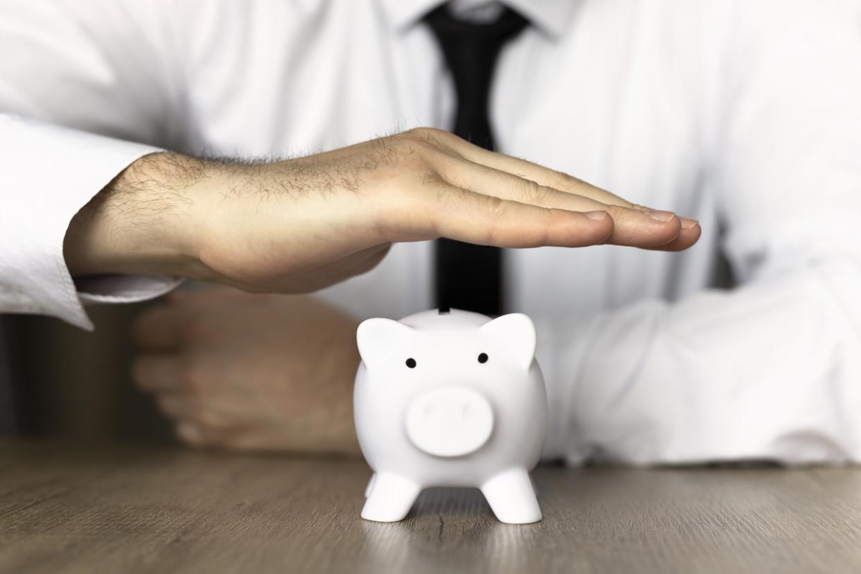 businessman with hand over piggy bank