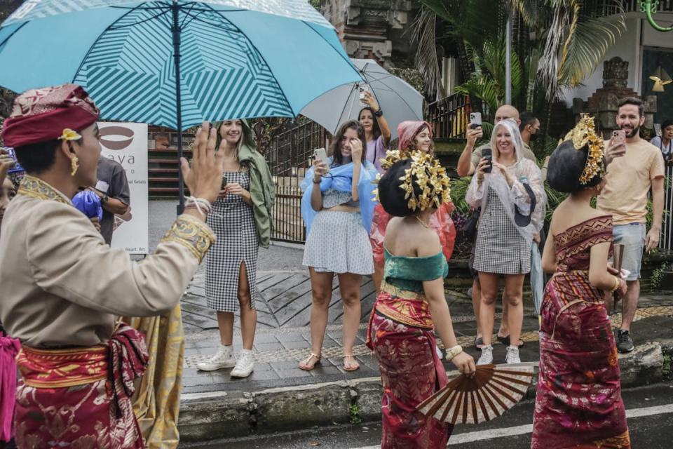 Tourists take pictures of Balinese artists during a parade celebrating the 77th anniversary of Indonesia Independence Day in Bali in August 2022. <a href="https://www.gettyimages.com/detail/news-photo/foreign-tourists-take-pictures-of-balinese-artists-during-news-photo/1242552941?adppopup=true" rel="nofollow noopener" target="_blank" data-ylk="slk:Johannes P. Christo/Anadolu Agency via Getty Images;elm:context_link;itc:0;sec:content-canvas" class="link ">Johannes P. Christo/Anadolu Agency via Getty Images</a>