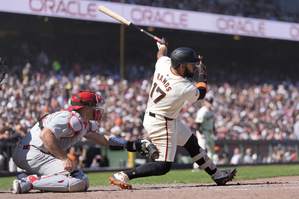 San Francisco Giants' Heliot Ramos (17) hits a two-run single in front of Philadelphia Phillies catcher J.T. Realmuto during the seventh inning of a baseball game in San Francisco, Monday, May 27, 2024. (AP Photo/Jeff Chiu)