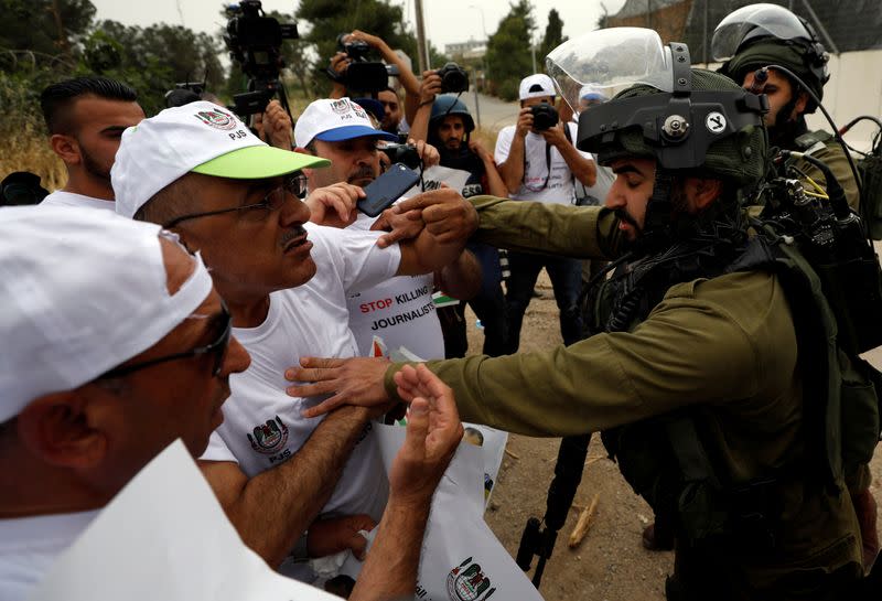 An Israeli soldier pushes back Palestinian journalists during a protest demanding freedom of the press, near Ramallah, in the occupied West Bank