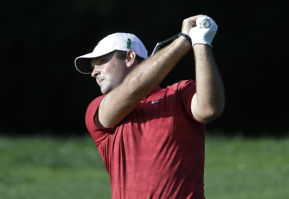 Patrick Reed wears a green ribbon on his hat in support of the victims of the University of North Carolina-Charlotte shooting as he watches his approach shot on the 12th hole during the first round of the Wells Fargo Championship golf tournament at Quail Hollow Club in Charlotte, N.C., Thursday, May 2, 2019. (AP Photo/Chuck Burton)