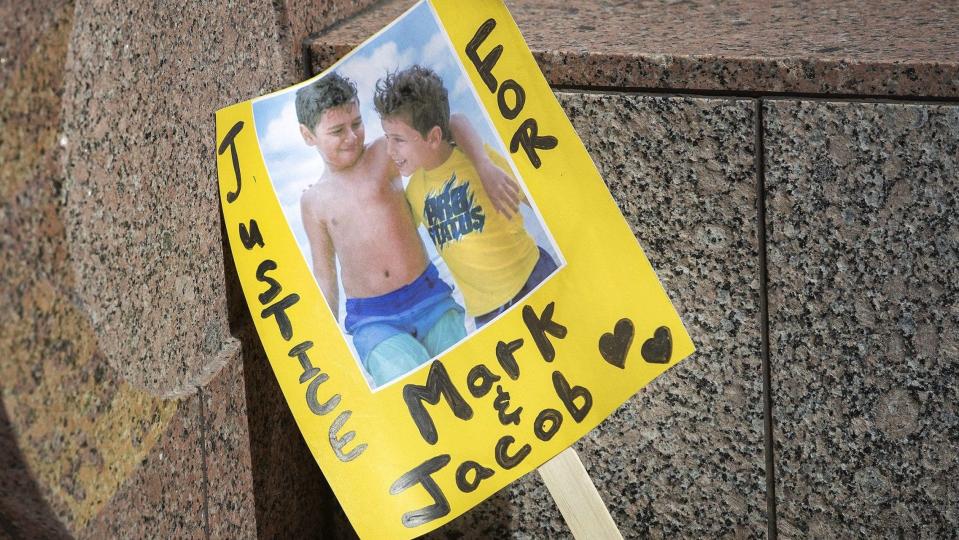 A sign shows an image of Mark Iskander, 11, left, and his brother Jacob, 8