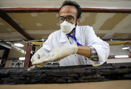 An Egyptian scientist works on restoring a piece of the second Khufu boat at a temporary laboratory set up next to the Great Pyramids where it was discovered, in Giza, Egypt March 29, 2017. REUTERS/Mohamed Abd El Ghany