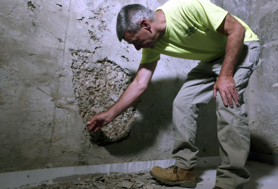 In this July 1, 2019 photo, contractor Don Childree pulls concrete from the wall of a crumbling house foundation in Vernon, Conn. The concrete foundation is deteriorating due to the presence of an iron sulfide known as pyrrhotite, often described as "a slow-moving disaster," which causes concrete to crack and break gradually as it becomes exposed to water and oxygen. After worrying for years about the foundations crumbling beneath their houses, hundreds of suburban homeowners in a large swath of eastern Connecticut are getting help from the state to salvage their properties that had been doomed by bad batches of concrete. (AP Photo/Ted Shaffrey)