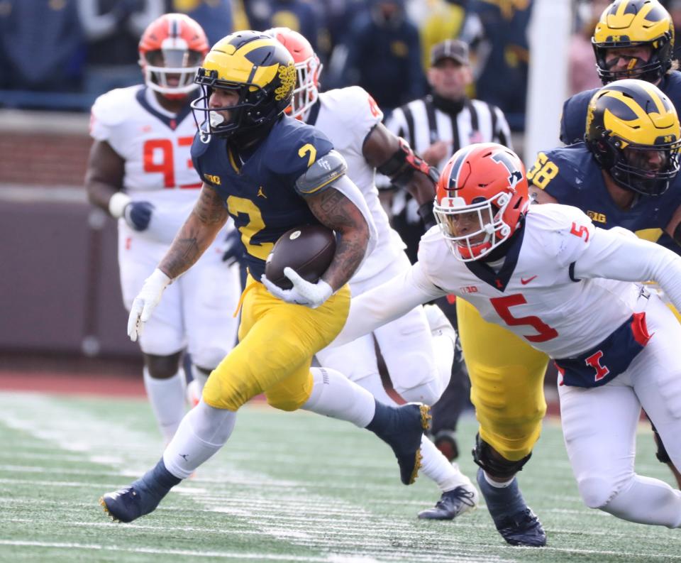 Michigan Wolverines running back Blake Corum runs by Illinois Fighting Illini linebacker Calvin Hart Jr. (5) during the first half at Michigan Stadium, Saturday, Nov. 19, 2022.