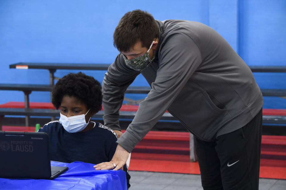 A staff member assists a child as they attend online classes at a learning hub inside the Crenshaw Family YMCA in Los Angeles on Feb. 17. The learning hub program provides distance-education resources while many area schools remain closed for in-person classes. (Photo: PATRICK T. FALLON via Getty Images)