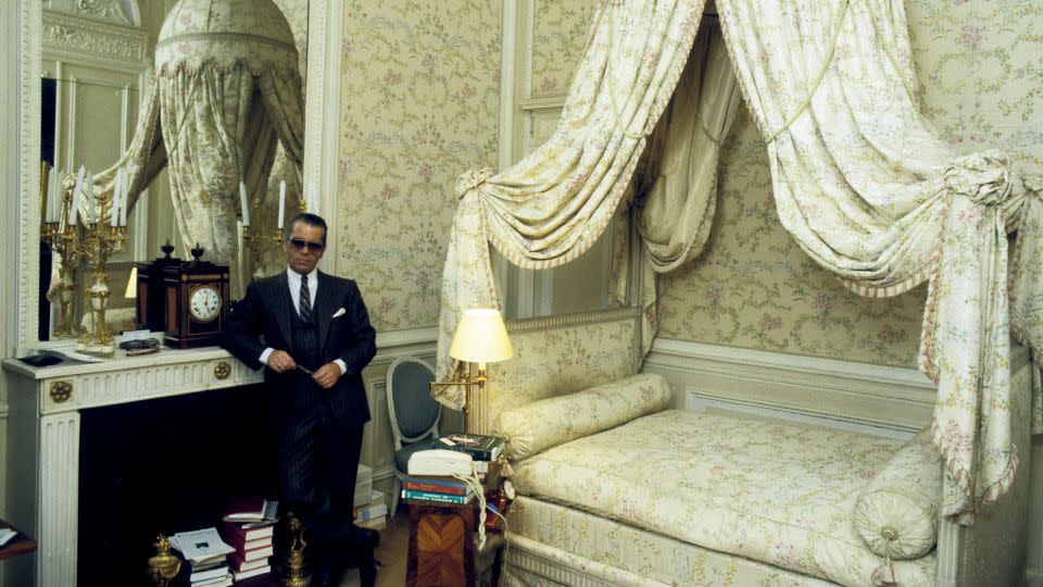 Lagerfeld in a bedroom at Villa La Vigie, his then-home in Roquebrune-Cap-Martin, southern France, in 1984 — the piles of books a nod to his love of reading, and a corded phone emblematic as a sign of the times (and, perhaps, an outlier, given the broader Regency-inspired theme). - A. Schorr/ullstein bild/Getty Images/Courtesy Thames & Hudson