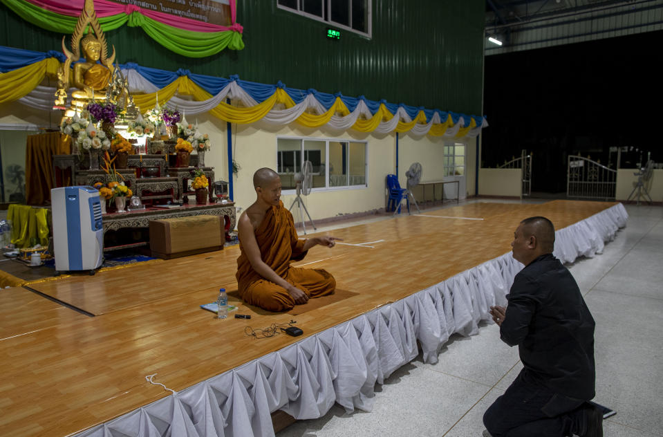In this Monday, Feb. 10, 2020 photo, Buddhist monk Phra Manaswin, left blesses Preecha Kitsanoh, right a surviver of shooting rampage at Wat Pa Sattharuam Buddhist temple in Nakhon Ratchasima, Thailand. The secluded temple complex in the northeastern Thai province had opened its gates for Buddha Day, allowing in dozens of devotees, when a rogue soldier from the neighboring Army base roared through in a stolen Humvee, fatally shooting nine people, including a 13-year-old boy, and injuring more. (AP Photo/Gemunu Amarasinghe)