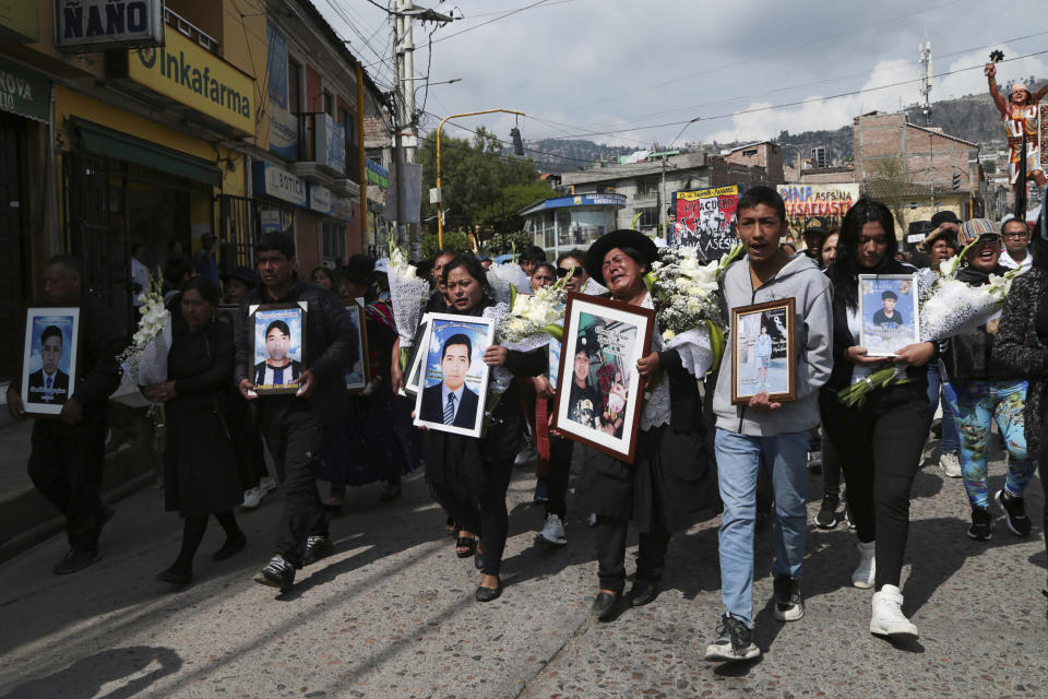 Personas caminando hacia el cementerio con las imágenes de sus familiares que fueron asesinados hace un año durante las protestas contra el gobierno en Ayacucho, Perú, el viernes 15 de diciembre de 2023. La Comisión Interamericana de Derechos Humanos y el Alto Comisionado de Derechos Humanos de la ONU han requerido al gobierno peruano que investigue las denuncias de uso excesivo de la fuerza pública en las protestas de hace un año que dejaron 49 civiles muertos. (AP Foto/Silvio La Rosa)