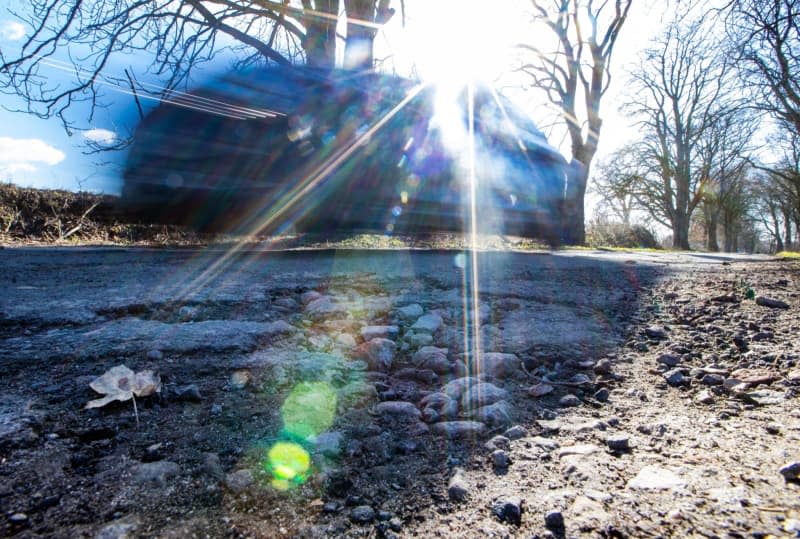 Potholes form when water from melting snow or rain seeps through cracks in the road surface when the weather is warm. Then, the liquid freezes and expands when temperatures fall, pushing a portion of the roadway and the ground upwards. Jens Büttner/dpa