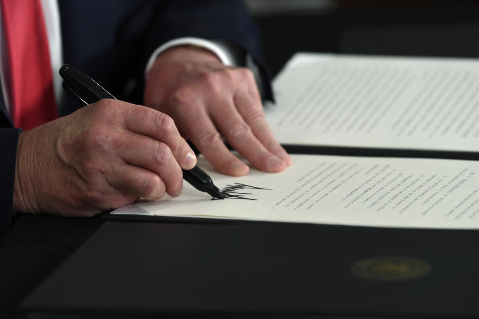 President Donald Trump signs an executive order during a news conference at the Trump National Golf Club in Bedminster, N.J., Saturday, Aug. 8, 2020. (AP Photo/Susan Walsh)