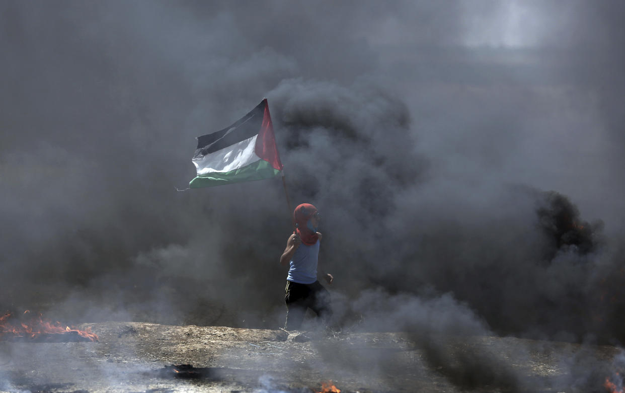 A boy waves a Palestinian flag during a protest on the Gaza Strip’s border with Israel (Picture: AP)