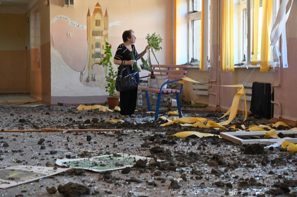 Eine Frau untersucht die Schäden in einer Schule in einem Wohnviertel der ukrainischen Stadt Charkiw, das von russischen Bomben getroffen wurde. - Copyright: Sergej Bobok/AFP via Getty Images