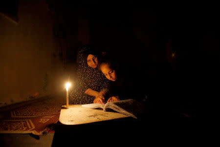 A Palestinian girl studies her lessons by a candlelight during power cut inside her family's house at Shati refugee camp in Gaza City April 25, 2017. REUTERS/Mohammed Salem