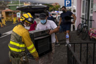 Residents remove their belongings from their houses as lava from a volcano eruption flows, as they are evacuated from their village in Los Llanos, on the island of La Palma in the Canaries, Spain, Wednesday, Sept. 22, 2021. A volcano on a small Spanish island in the Atlantic Ocean erupted on Sunday, forcing the evacuation of thousands of people. Experts say the volcanic eruption and its aftermath on a Spanish island could last for up to 84 days. The Canary Island Volcanology Institute said Wednesday it based its calculation on the length of previous eruptions on the archipelago. (AP Photo/Emilio Morenatti)