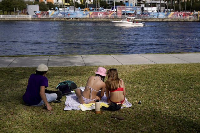 FILE - In this Feb. 5, 2021, file photo, college students study in the sun while people on the other side of the Hillsborough River take part in Super Bowl 55 activities in Tampa, Fla. The city is hosting Sunday's Super Bowl football game between the Tampa Bay Buccaneers and the Kansas City Chiefs. (AP Photo/Charlie Riedel, File)