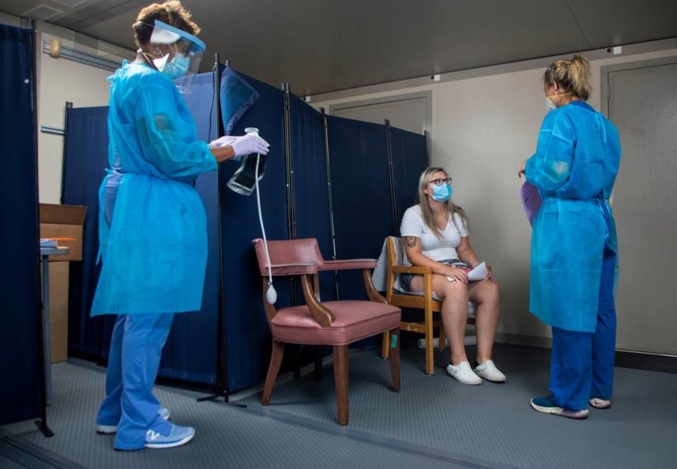 Emmily Mangum, middle, talks with health care workers Lauren Drapiza, right, and Talia Roofe, left, while under observation after receiving monoclonal antibody treatment for COVID-19 at a mobile clinic in the Johnston County Public Health Department parking lot in Smithfield, N.C., on Wednesday, Sept. 15, 2021.