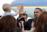 Barack Obama choca las manos con un niño mientras saluda a la multitud reunida para recibirlo en la Base de la Fuerza Aérea Buckley, el martes 24 de abril de 2012, en Aurora, Colorado. (AP Photo/Carolyn Kaster)