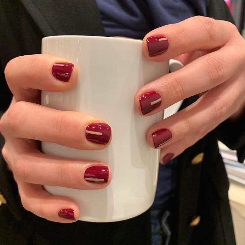 Very few manicures scream "fall" quite like a shade of dark red. But if you're tired of the same old same old, check out <a href="https://www.instagram.com/p/BssliESgT0G/" rel="nofollow noopener" target="_blank" data-ylk="slk:this update;elm:context_link;itc:0;sec:content-canvas" class="link ">this update</a> by nontoxic New York City nail salon Tenoverten. Not too thick, not too thin, partial stripes in a creamy white shade add interest to a timeless look.