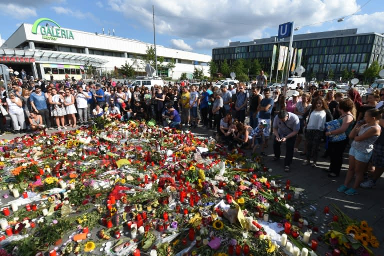 People mourn at a memorial of candles and flowers on July 24, 2016 in front of the Olympia Einkaufszentrum shopping centre in Munich, southern Germany, where an 18-year-old German-Iranian student run amok