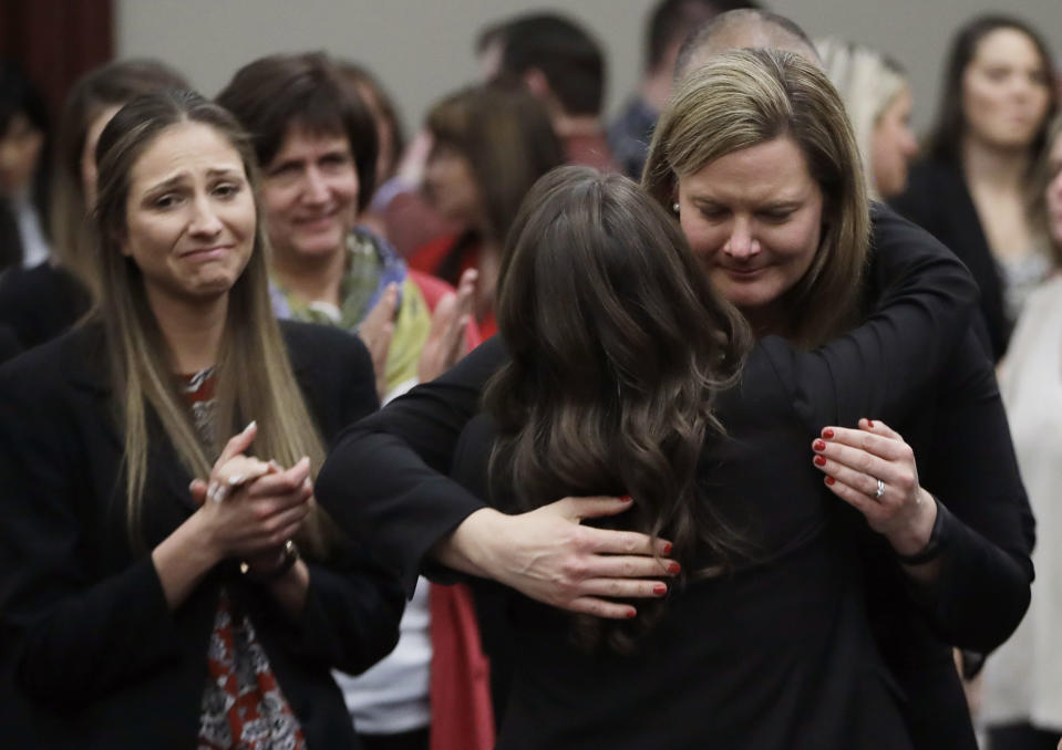 FILE -In this Jan. 24, 2018, file photo, victims react and hug Assistant Attorney General Angela Povilaitis after Larry Nassar was sentenced by Judge Rosemarie Aquilina to 40 to 175 years in prison during a sentencing hearing in Lansing, Mich. The U.S. Justice Department announced a $138.7 million settlement Tuesday, April 23, 2024, with more than 100 people who accused the FBI of grossly mishandling allegations of sexual assault against Larry Nassar in 2015 and 2016, a critical time gap that allowed the sports doctor to continue to prey on victims before his arrest. (AP Photo/Carlos Osorio, File)