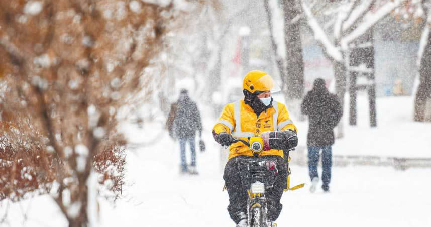 新疆烏魯木齊市日前迎來一場大雪，1名外送員頂著寒風在路上送餐。（新華社）