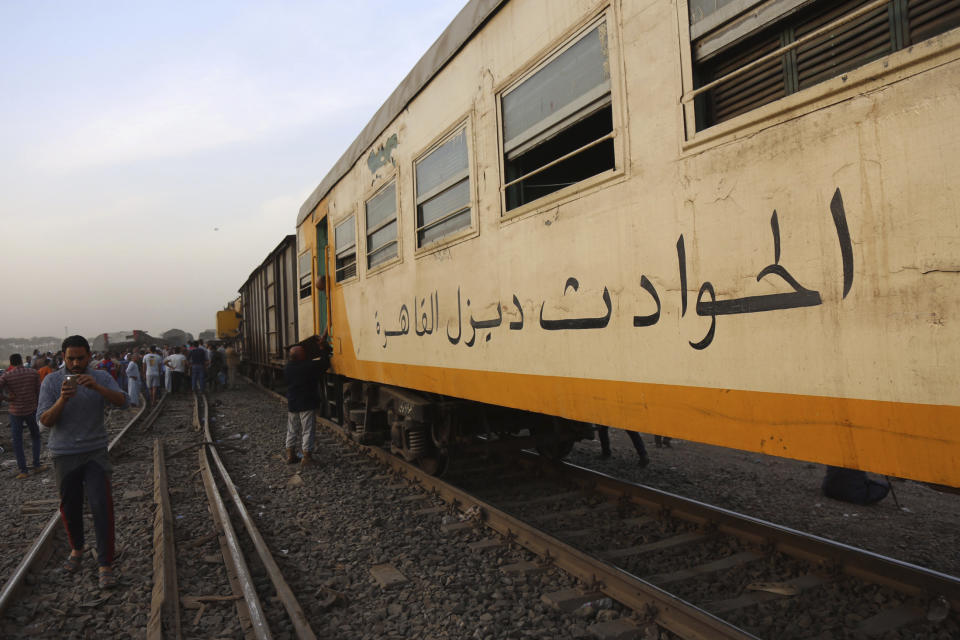 People take photos with their mobile phones at the site of a passenger train that derailed injuring some 100 people, near Banha, Qalyubia province, Egypt, Sunday, April 18, 2021. At least eight train wagons ran off the railway, the provincial governor's office said in a statement. (AP Photo/Fadel Dawood)