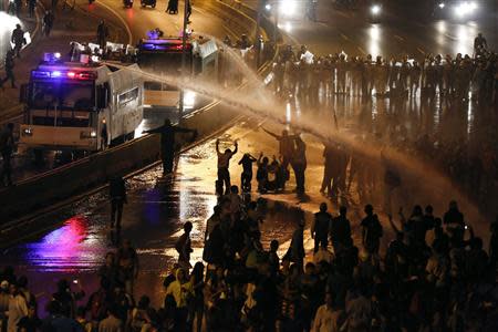 Riot police use water to disperse opposition demonstrators as they block the city's main highway during a protest against Nicolas Maduro's government in Caracas February 14, 2014. REUTERS/Carlos Garcia Rawlins