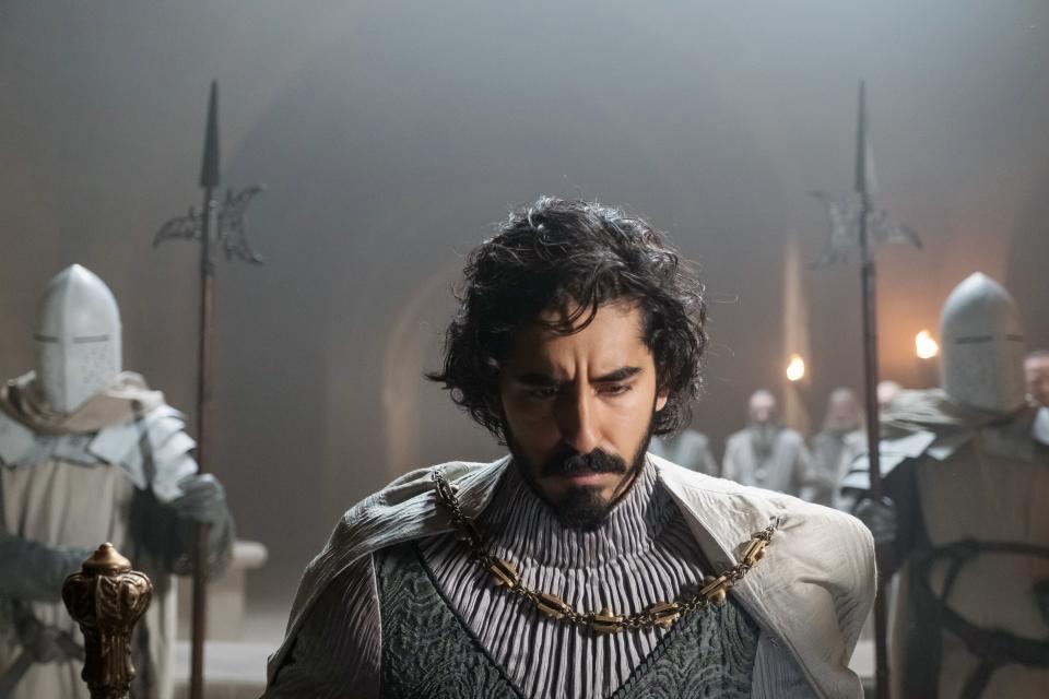 Dev Patel kneels in a hall