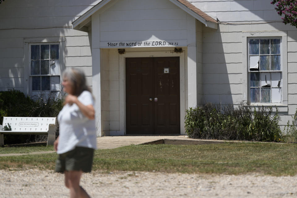 A woman visits the First Baptist Church in Sutherland Springs, Texas, Tuesday, July 2, 2024, which is now a memorial to the 26 people who were killed by a gunman in 2017. The 100-year-old building has served as a memorial since the shooting, but now some want to raze the building. (AP Photo/Eric Gay)