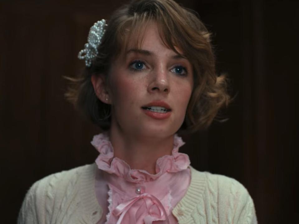 maya hawke as robin in stranger things, with a passionate expression on her face and wearing a frilly pink collar