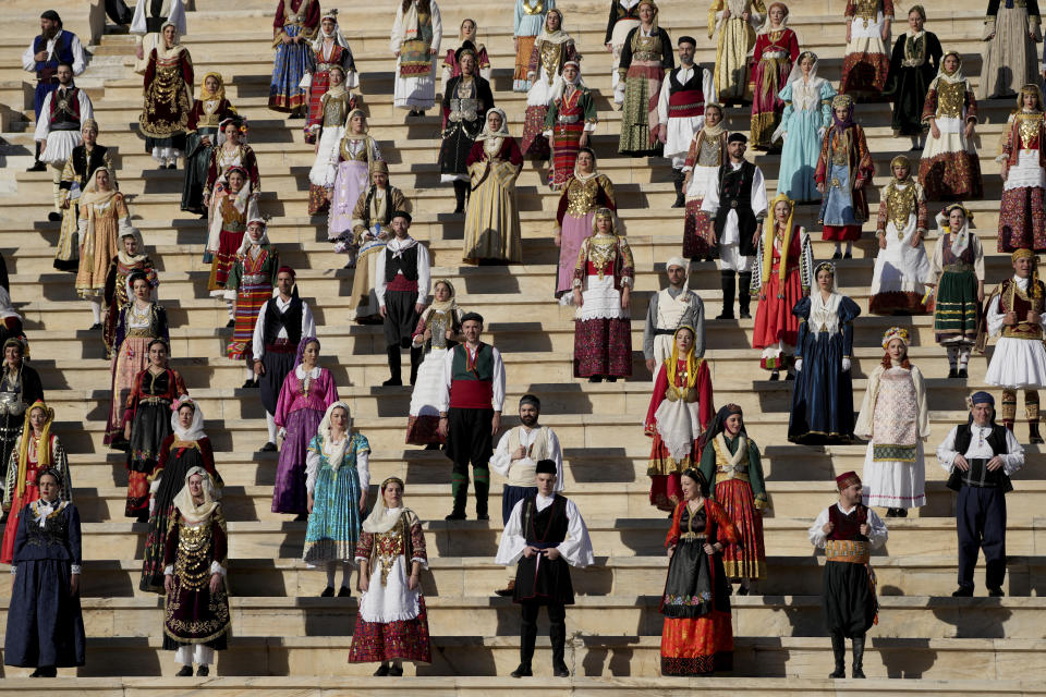 Performers wear different Greek traditional costumes during the Olympic flame handover ceremony at Panathenaic stadium, where the first modern games were held in 1896, in Athens, Friday, April 26, 2024. On Saturday the flame will board the Belem, a French three-masted sailing ship, built in 1896, to be transported to France. (AP Photo/Petros Giannakouris)