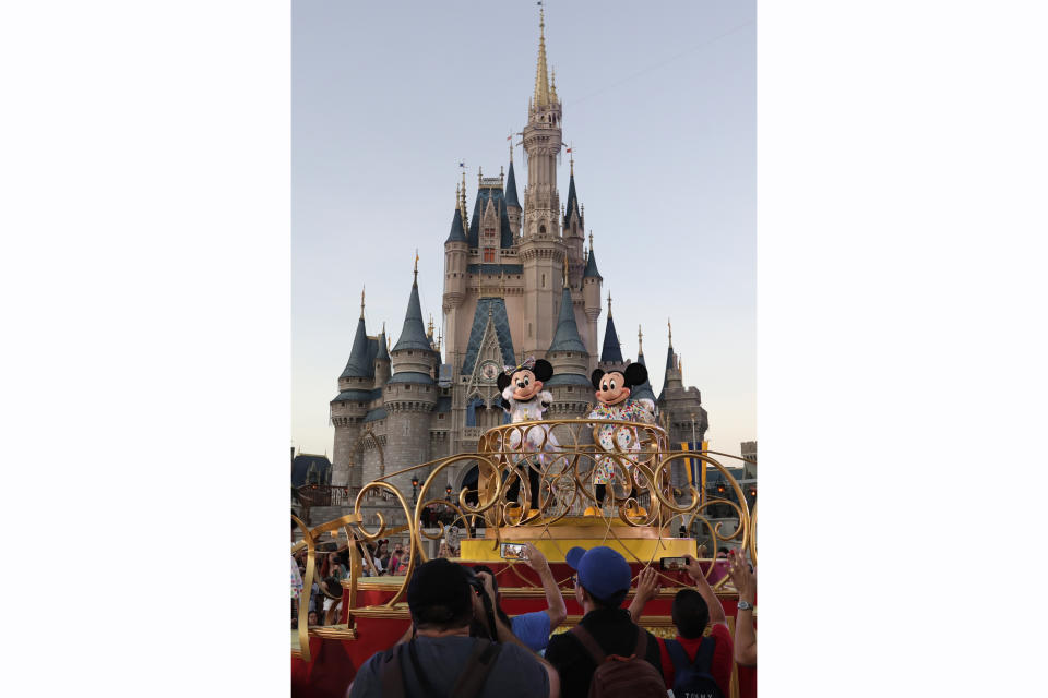 FILE - Mickey and Minnie Mouse perform during a parade as they pass by the Cinderella Castle at the Magic Kingdom theme park at Walt Disney World in Lake Buena Vista, Fla., on Wednesday, Jan. 15, 2020. Tens of thousands of LGBTQ+ people are flocking to Florida's theme parks and hotels to go on thrill rides, dance at all-night parties and lounge poolside in a decades-long tradition known as Gay Days. Even though Gov. Ron DeSantis and Florida lawmakers have championed a slew of anti-LGBTQ laws, that's not stopping organizers from encouraging visitors from around the world to come and visit. (AP Photo/John Raoux, File)