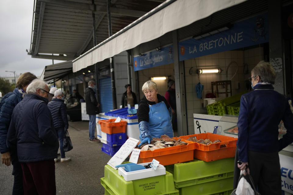 People buy fish at the market of the port of Boulogne-sur-Mer, northern France, Friday, Oct. 15, 2021. France wants more fishing licenses from London, but the UK is holding back. Britain's Brexit minister accused the EU of wishing failure on its former member and of badmouthing the U.K. as a country that can't be trusted. (AP Photo/Christophe Ena)