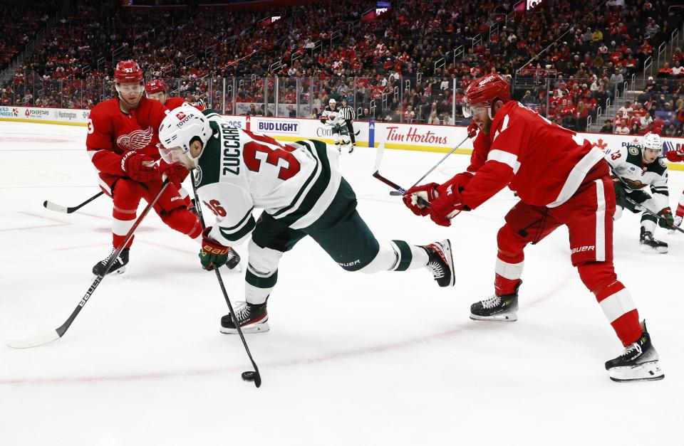 Minnesota Wild right wing Mats Zuccarello (36) moves the puck against Detroit Red Wings left wing J.T. Compher, right, and defenseman Moritz Seider (53) during the second period of an NHL hockey game Sunday, Nov. 26, 2023, in Detroit. (AP Photo/Duane Burleson)