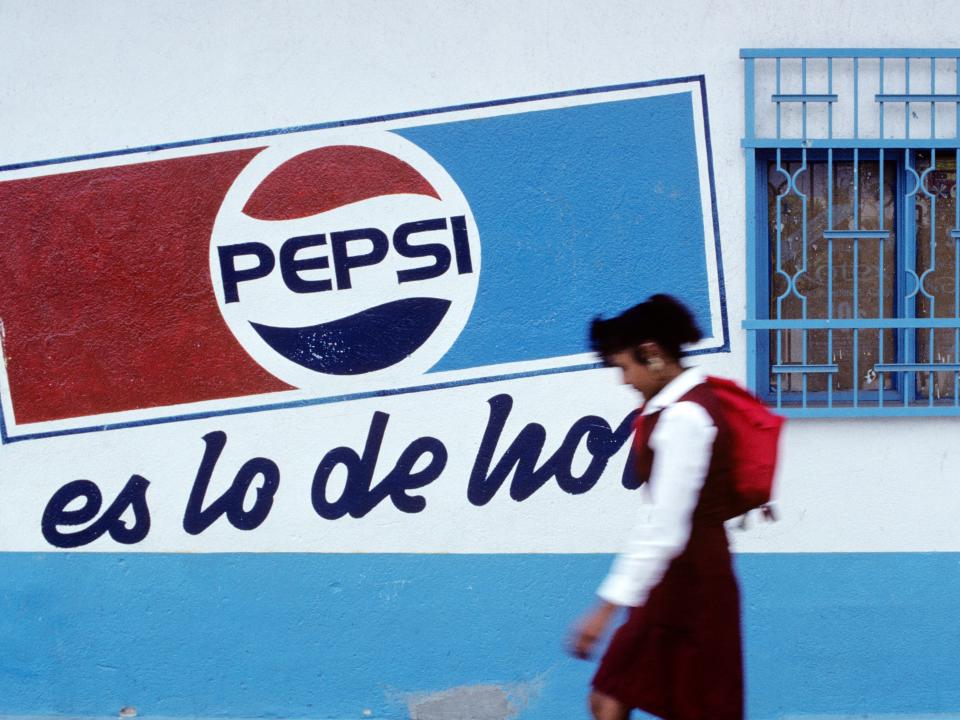 A schoolgirl walks past a Pepsi advertisement in 1990 Mexico, showing the old logo similar to today's.