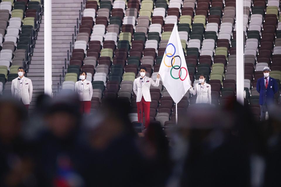 The Olympic flag is raised in front of the Olympic cauldron during the Opening Ceremony of the Tokyo 2020 Olympic Games at Olympic Stadium.