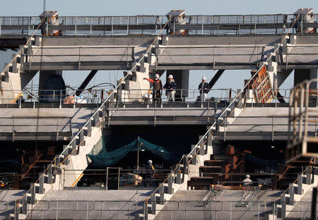 Men work at the construction site of the New National Stadium, the main stadium of Tokyo 2020 Olympics and Paralympics, in Tokyo, Japan December 22, 2017. REUTERS/Issei Kato