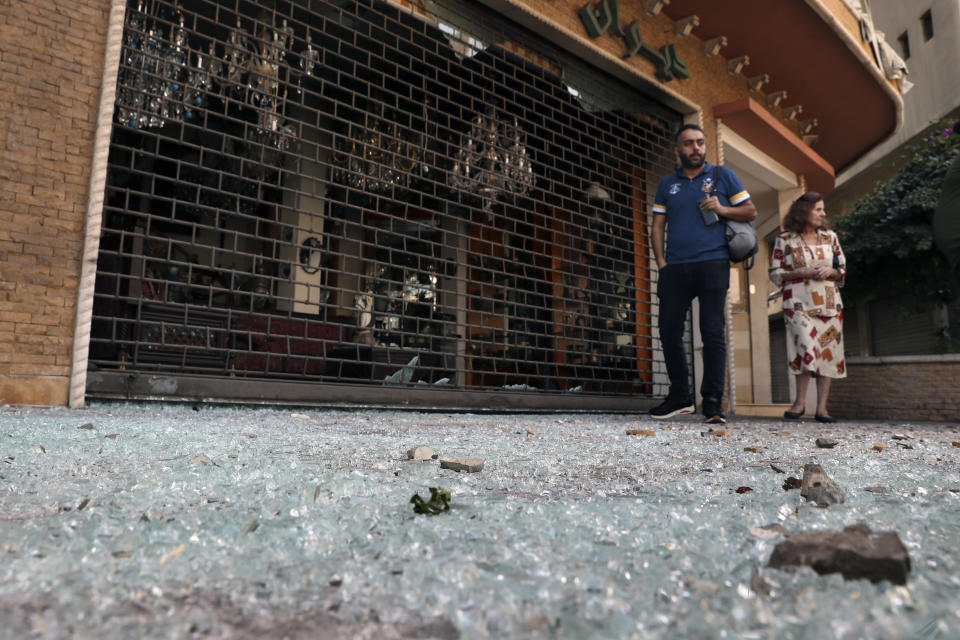 People walk on the glass of broken windows littering a street from deadly clashes that erupted Thursday along a former 1975-90 civil war front-line between Muslim Shiite and Christian areas, in Ain el-Remaneh neighborhood, Beirut, Lebanon, Friday, Oct. 15, 2021. Schools, banks and government offices across Lebanon shut down Friday after hours of gun battles between heavily armed militias killed six people and terrorized the residents of Beirut. (AP Photo/Bilal Hussein)