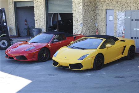 Two sports cars sit in a police impound lot in Miami Beach, Florida January 23, 2014. REUTERS/ Gary I. Rothsein
