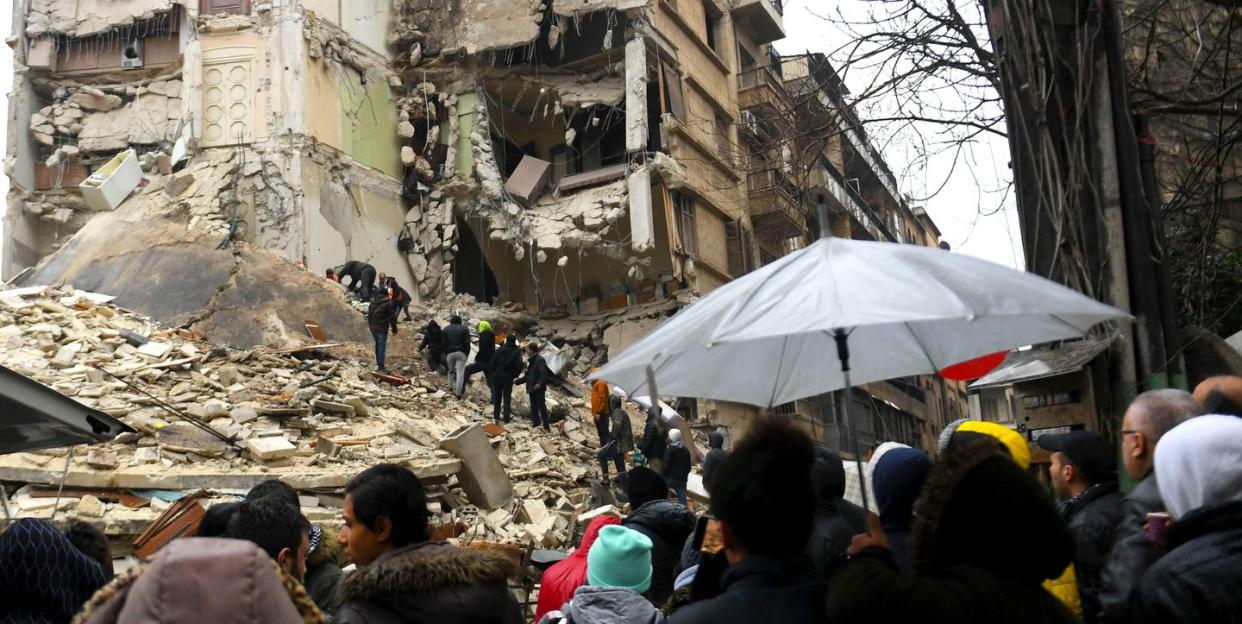 onlookers watch as rescue teams look for survivors under the rubble of a collapsed building after an earthquake in the regime controlled northern syrian city of aleppo on february 6 2023