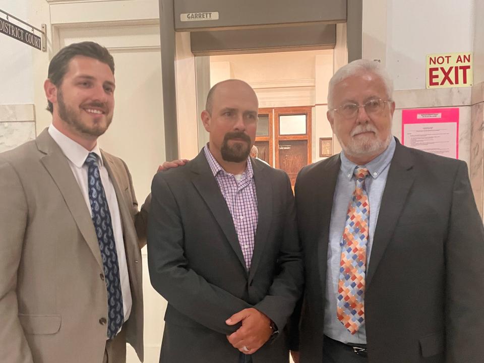 Lee Jordan, center, poses for a photo with his attorneys, Jared Perkins, left, and Eric Perkins, after the former officer was acquitted of felony injury to a child on May 4, 2022.