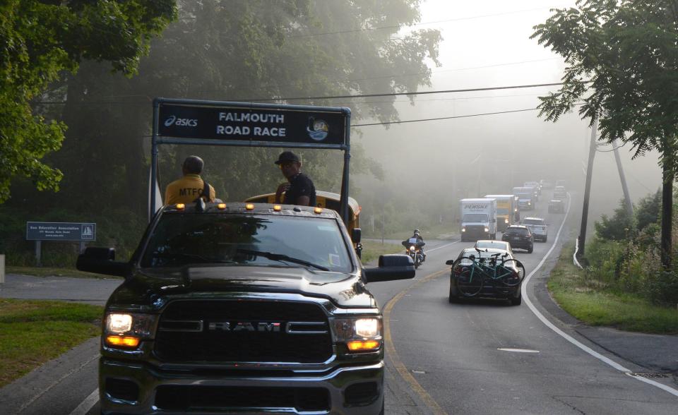 The Falmouth Road Race motorcade cuts through a foggy Woods Hole road making its way to the starting line.